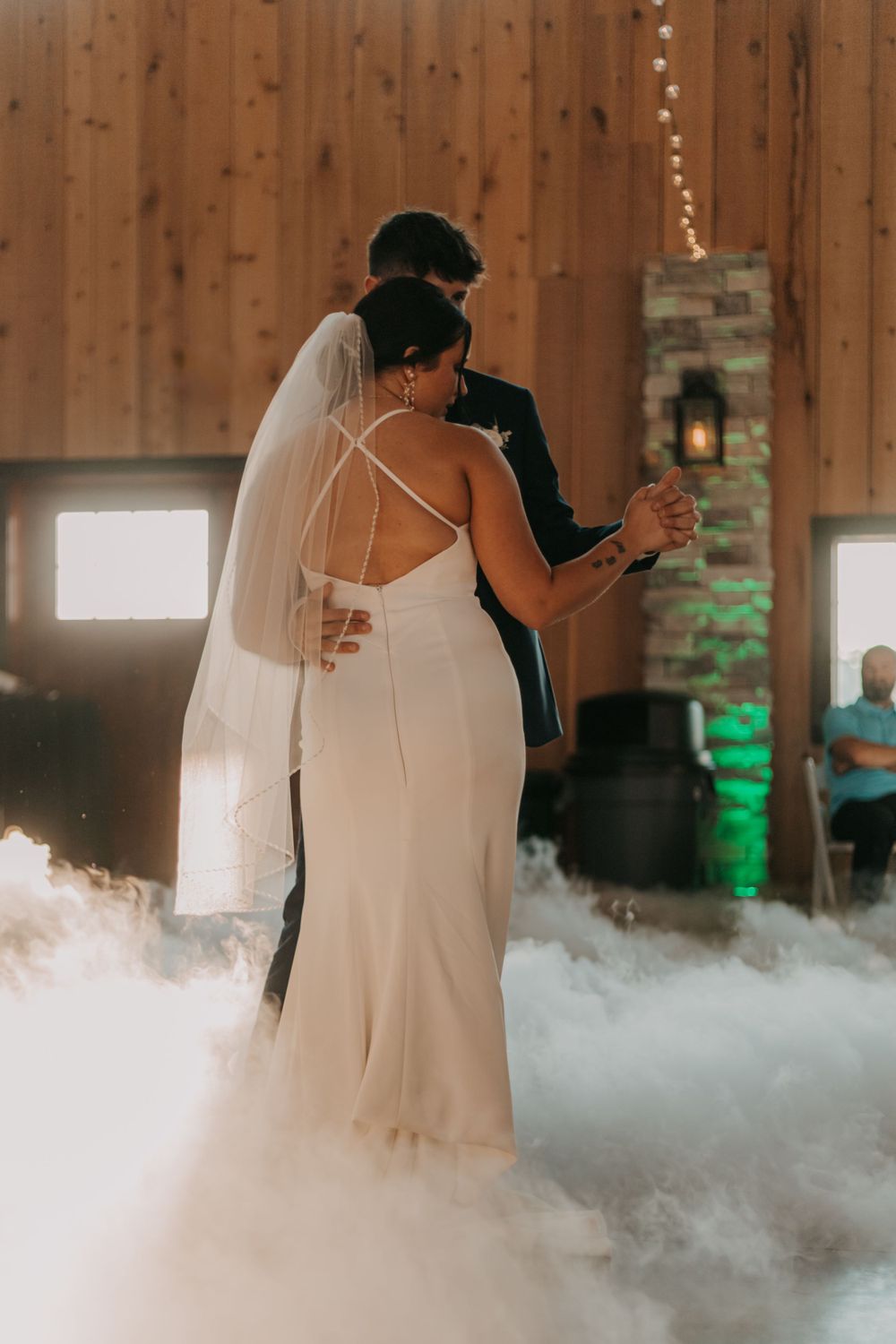 Couple dancing surrounded by atmospheric fog effect on wedding dance floor.