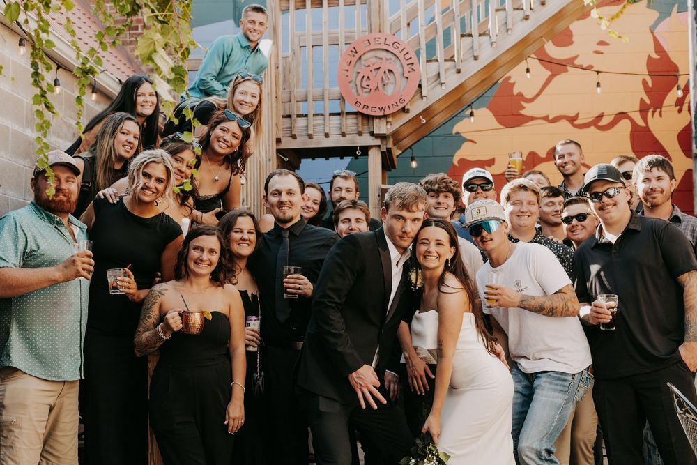 A joyful group celebrates at an outdoor venue with colorful wall art and industrial decor in the background.