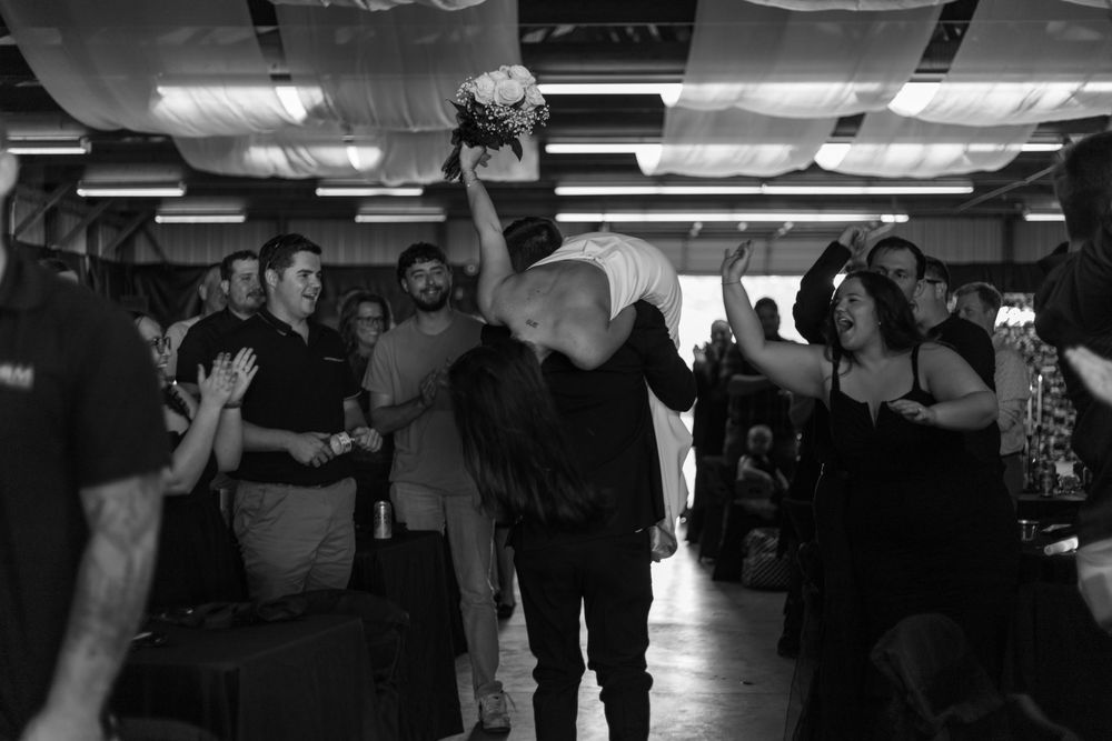 Black and white photograph of people exercising in a dimly lit gym with equipment and machines visible.