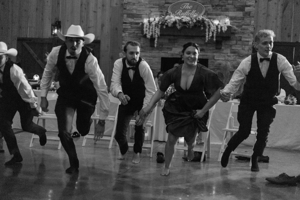Wedding party performs synchronized country dance routine in rustic venue.