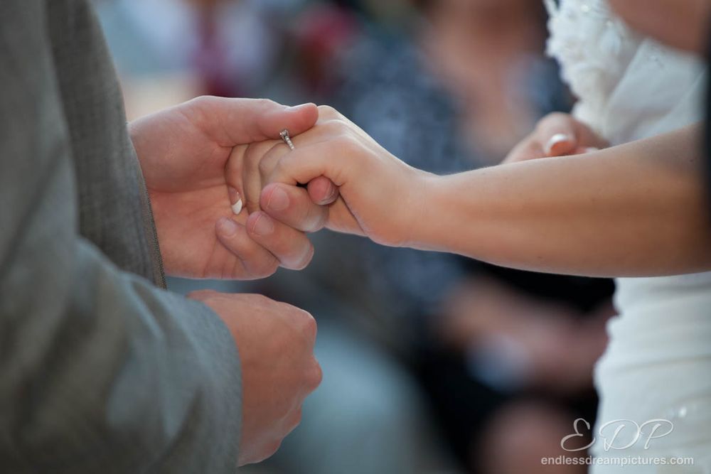 Close-up of hands exchanging wedding rings during ceremony.