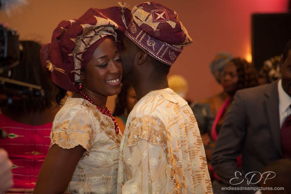 Couple in traditional African attire sharing a joyful moment at a celebration.
