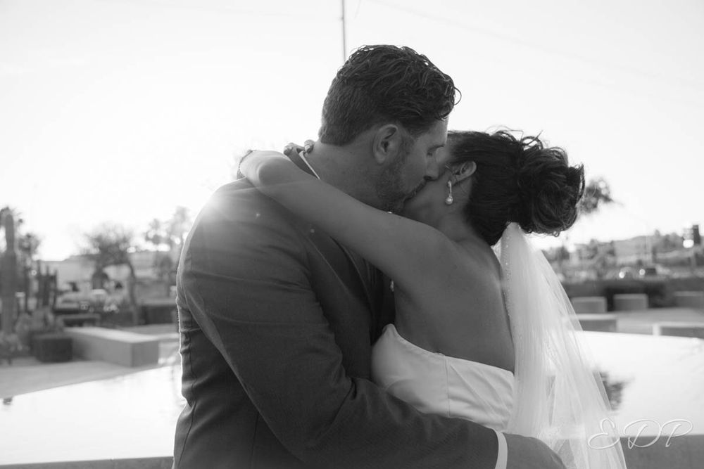Black and white silhouette of newlyweds sharing intimate moment at sunset.