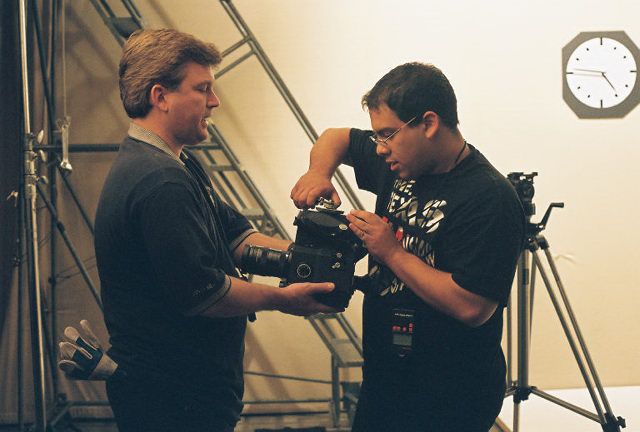 Two camera operators discussing equipment settings and reviewing footage on a professional video camera.