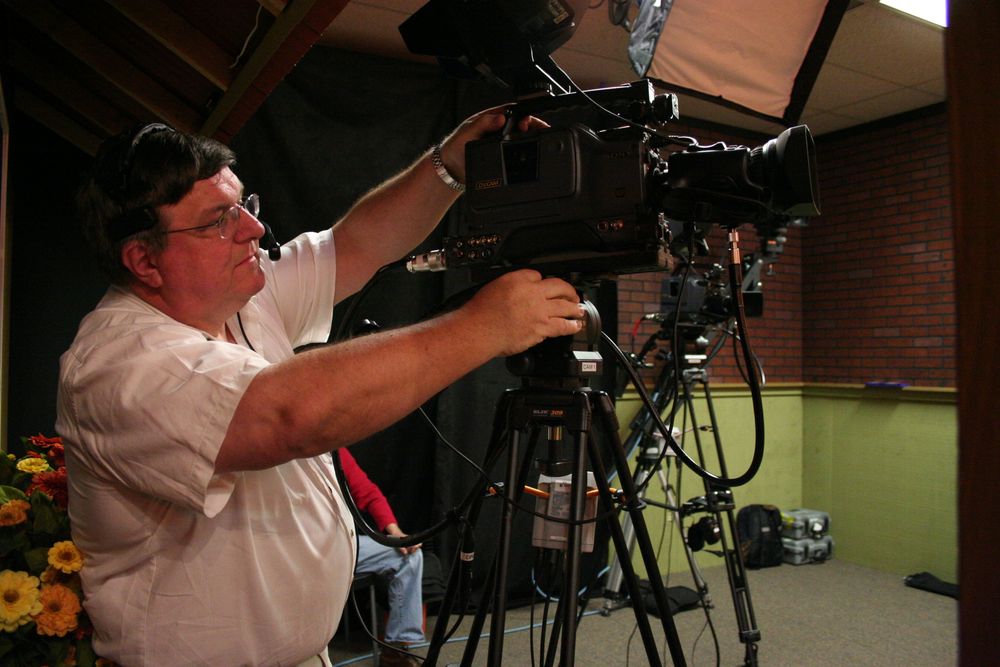 Camera operator adjusting professional video equipment during studio production.