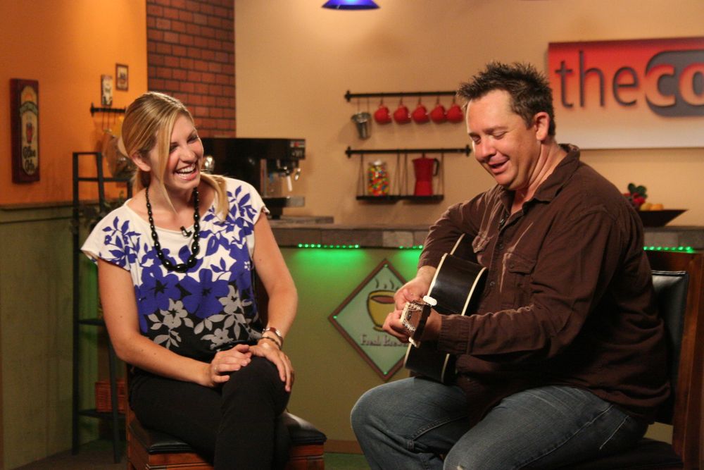 Musicians performing together in a casual cafe setting with acoustic guitar.