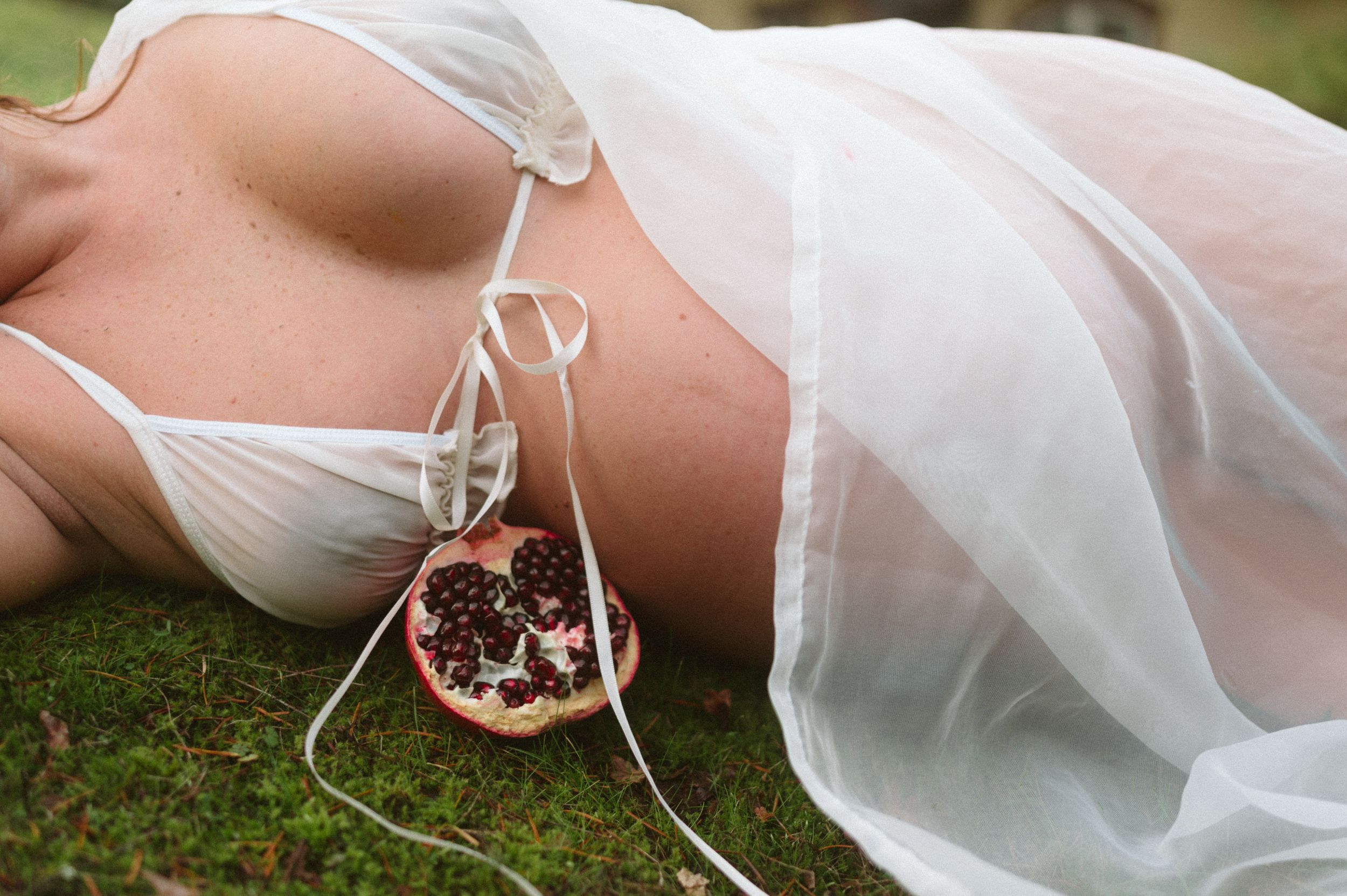 Artistic boudoir photo with delicate white lingerie and sheer fabric.