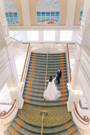 Elegant circular grand staircase with emerald green carpet and ornate details in a luxury venue with ocean view windows.