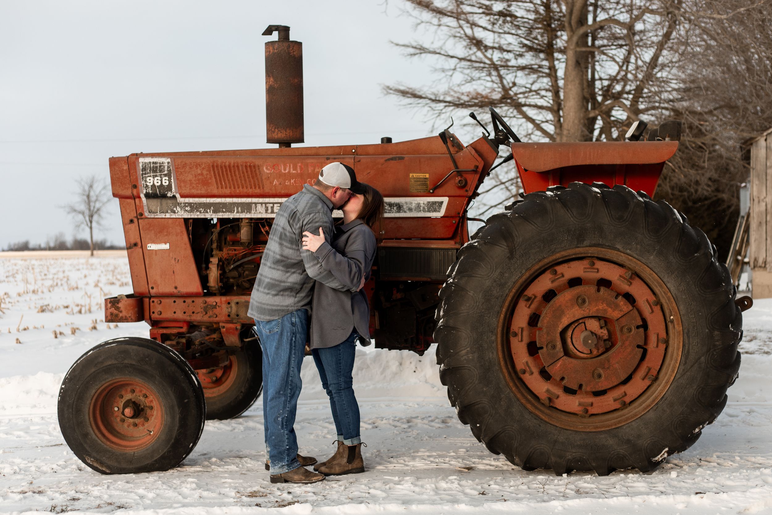 A series of photos showing someone standing next to a vintage red tractor in snowy winter conditions.