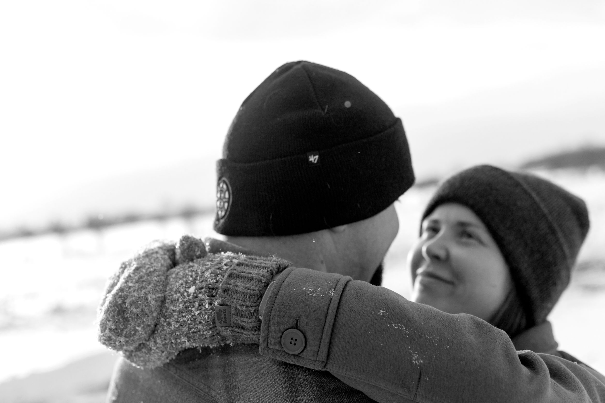 A black and white panoramic photo shows a group of people sitting together in winter hats and coats.