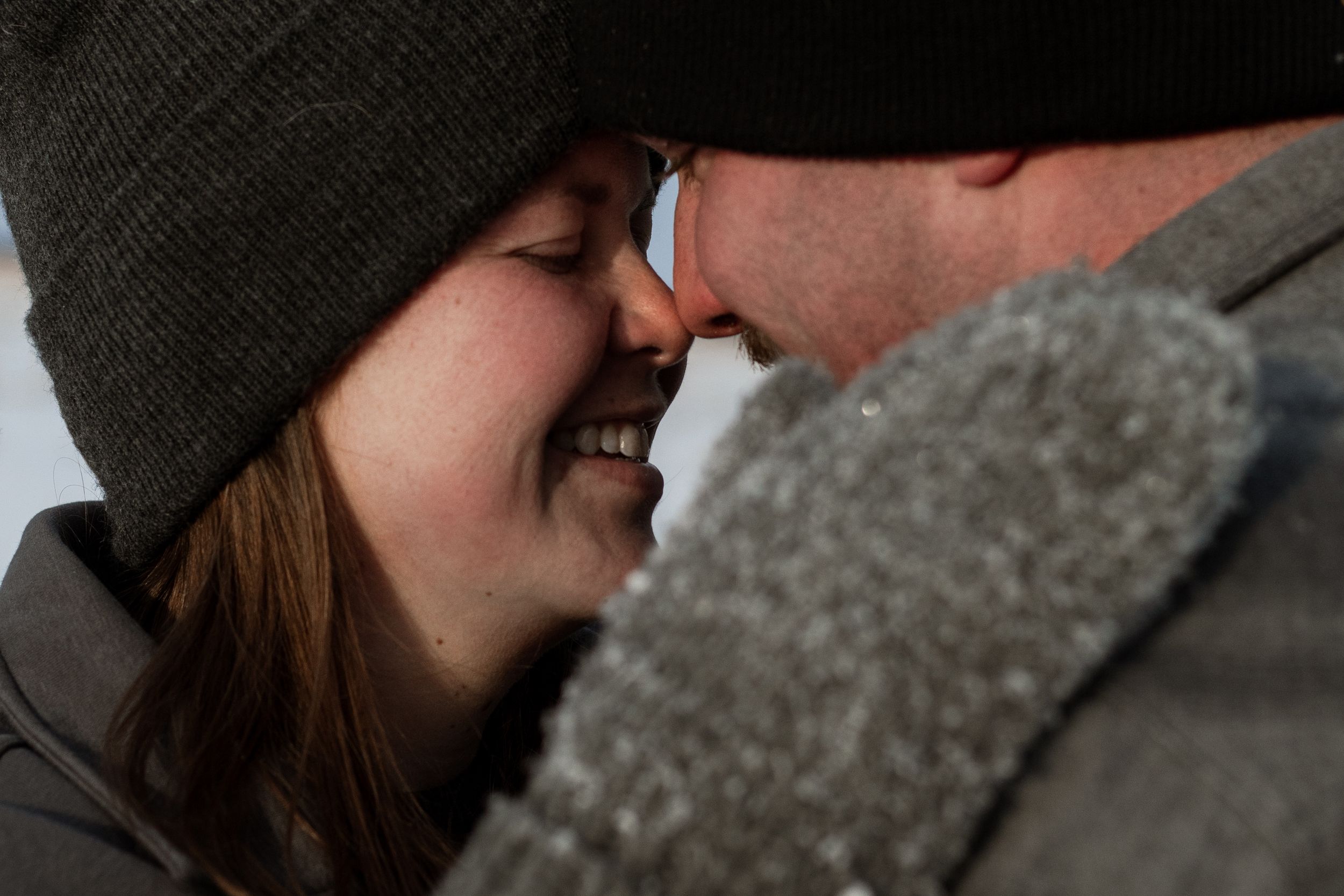 Close-up profile view of someone wearing a green beanie sharing an intimate moment in winter clothing.