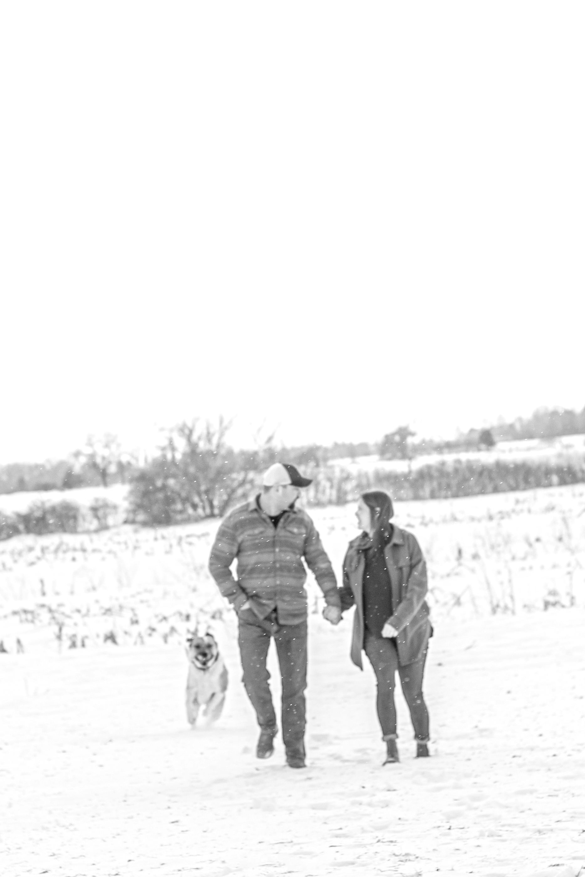A black and white photograph shows several people walking through a snowy winter landscape.