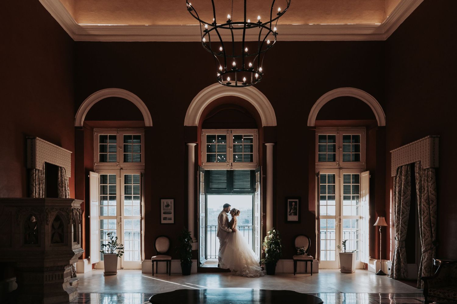 Elegant ballroom interior with arched windows and chandelier creating a dramatic atmosphere.