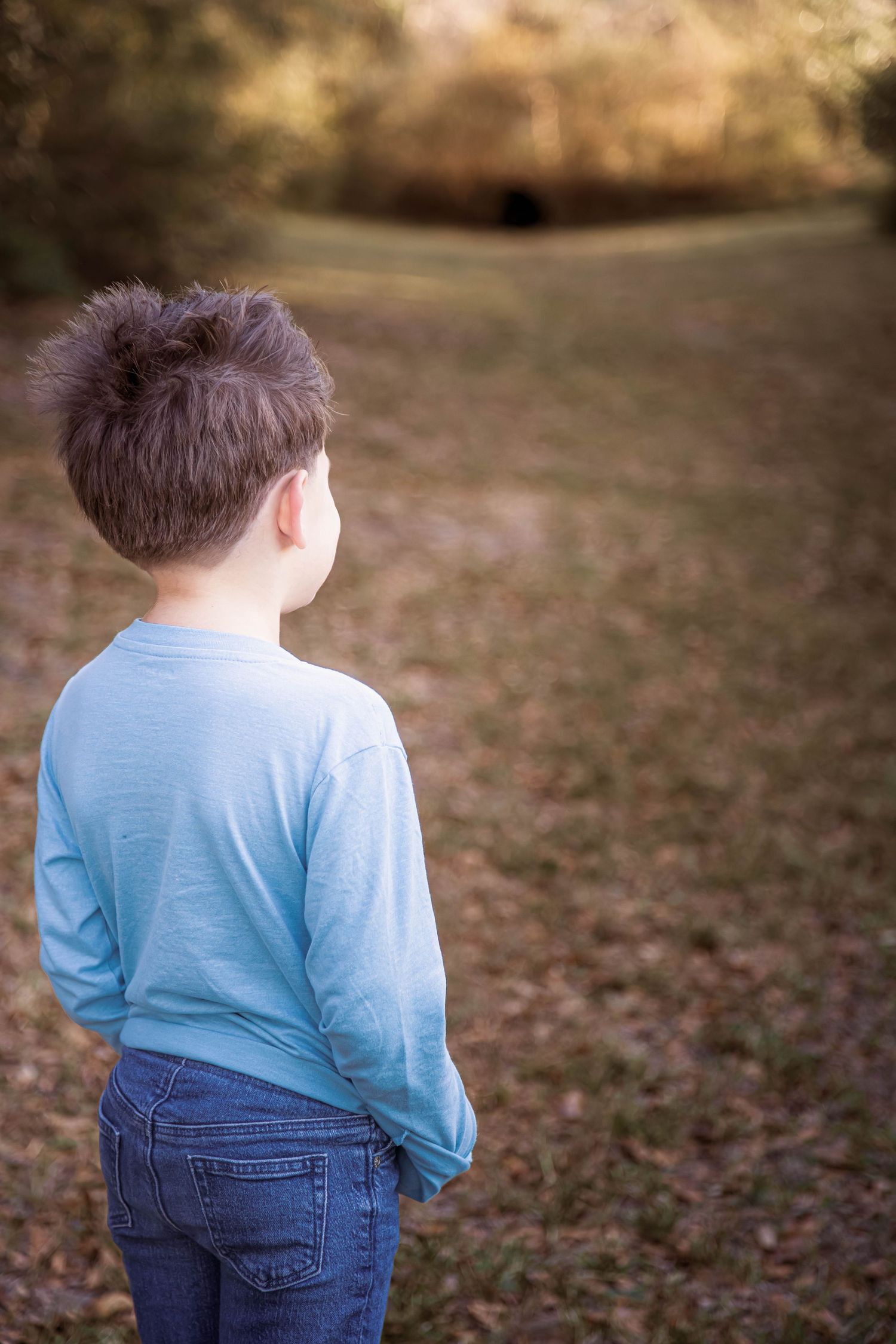 A sequence of candid outdoor portraits showing a young child in a light blue henley shirt and jeans against a blurred autumn background.