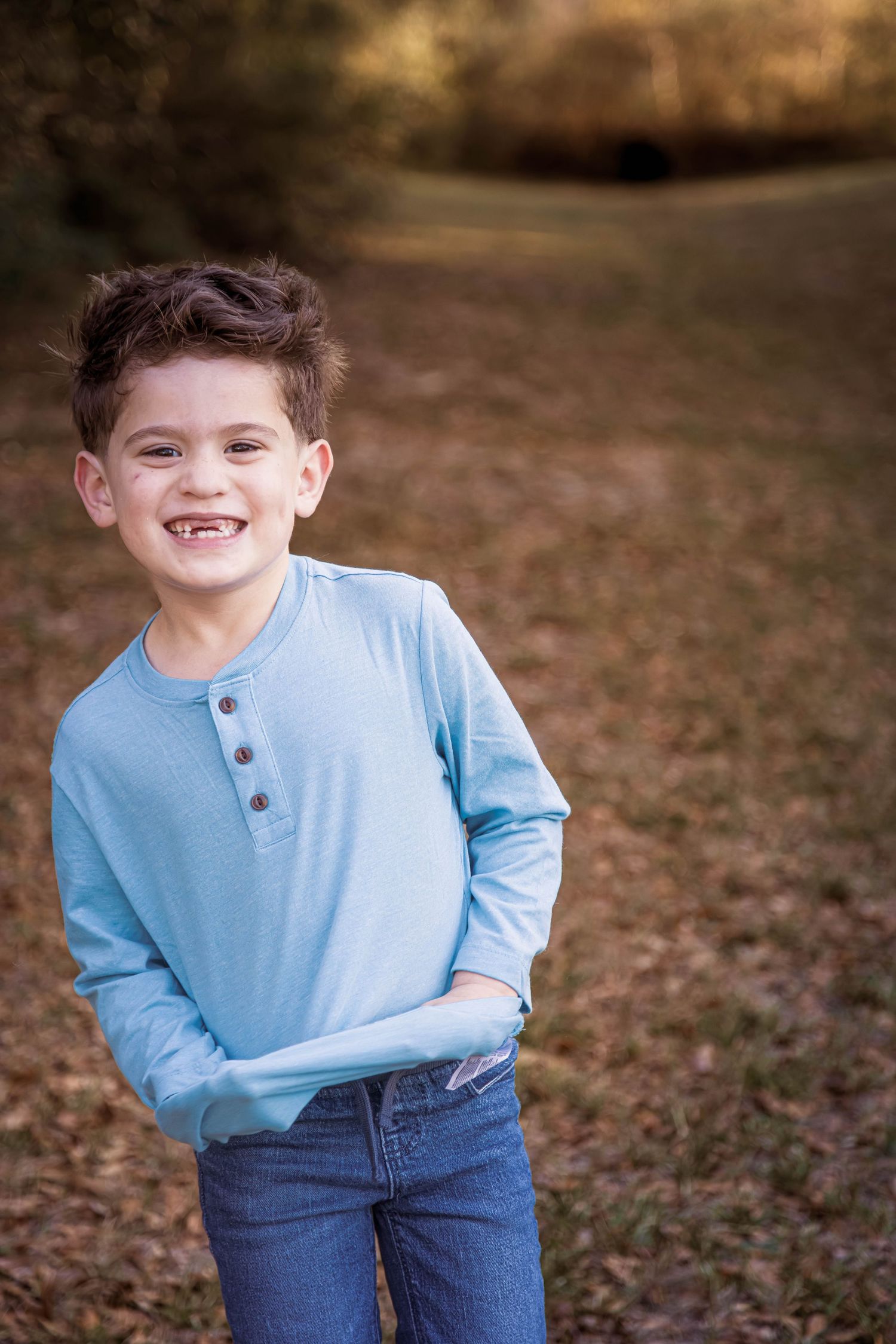 A series of four outdoor portraits showing a child in a light blue henley shirt and jeans against an autumn background.