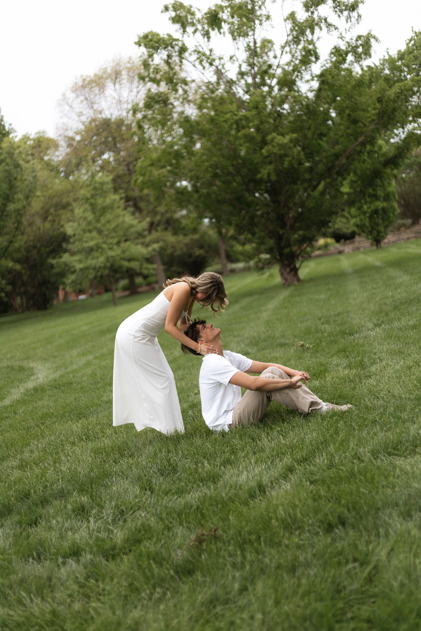 Young couple smiling and embracing outdoors on a green lawn.