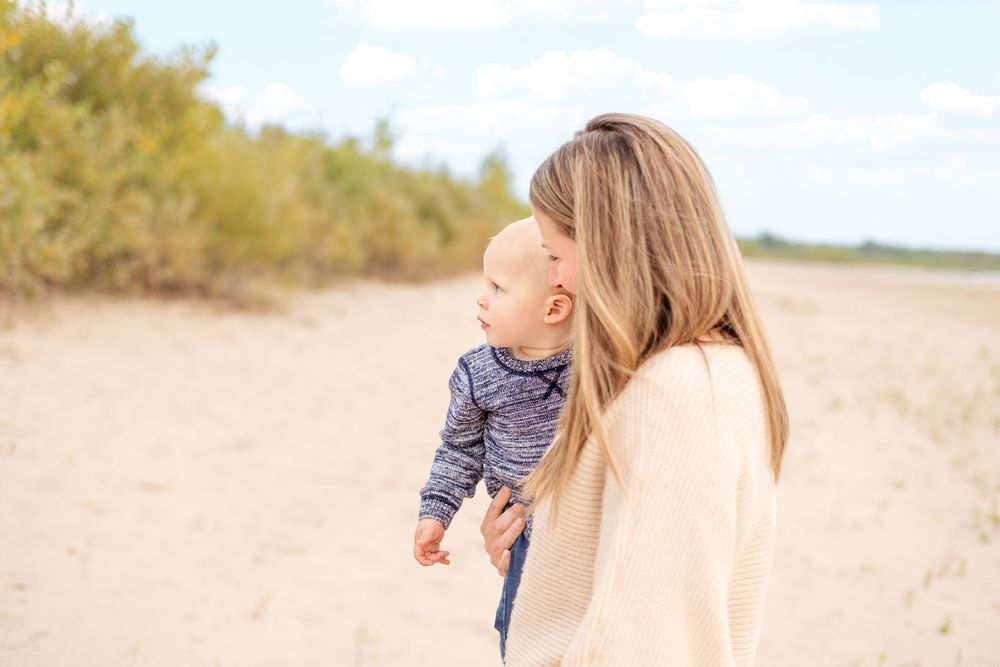 A parent and child share a tender moment together on a beach on a sunny afternoon.