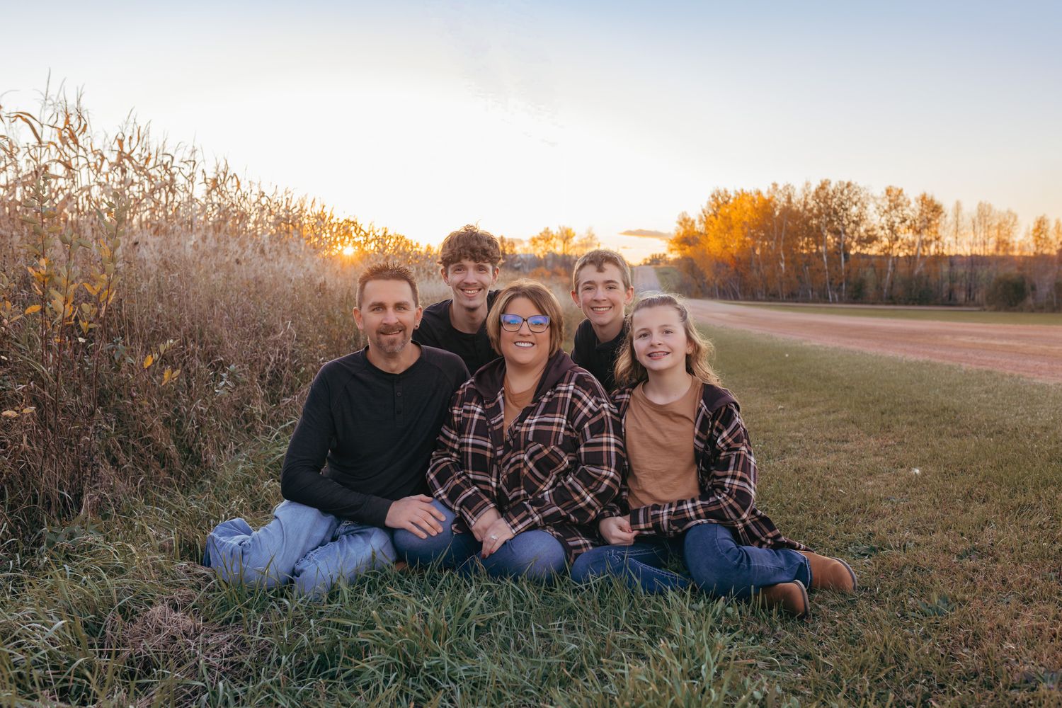 Family sitting close by a corn field at sunset