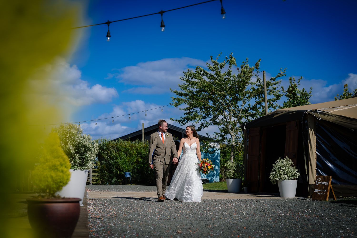 A scenic outdoor wedding venue with string lights and blue sky on a bright sunny day.