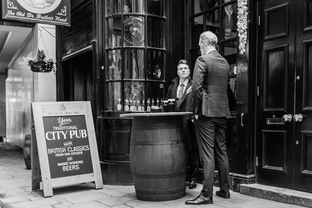Black and white photos of people walking past storefronts and city pub signs on a busy street.