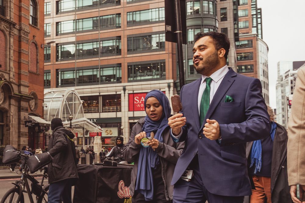 A group of people in business attire having an animated conversation outside a brick building in the city.