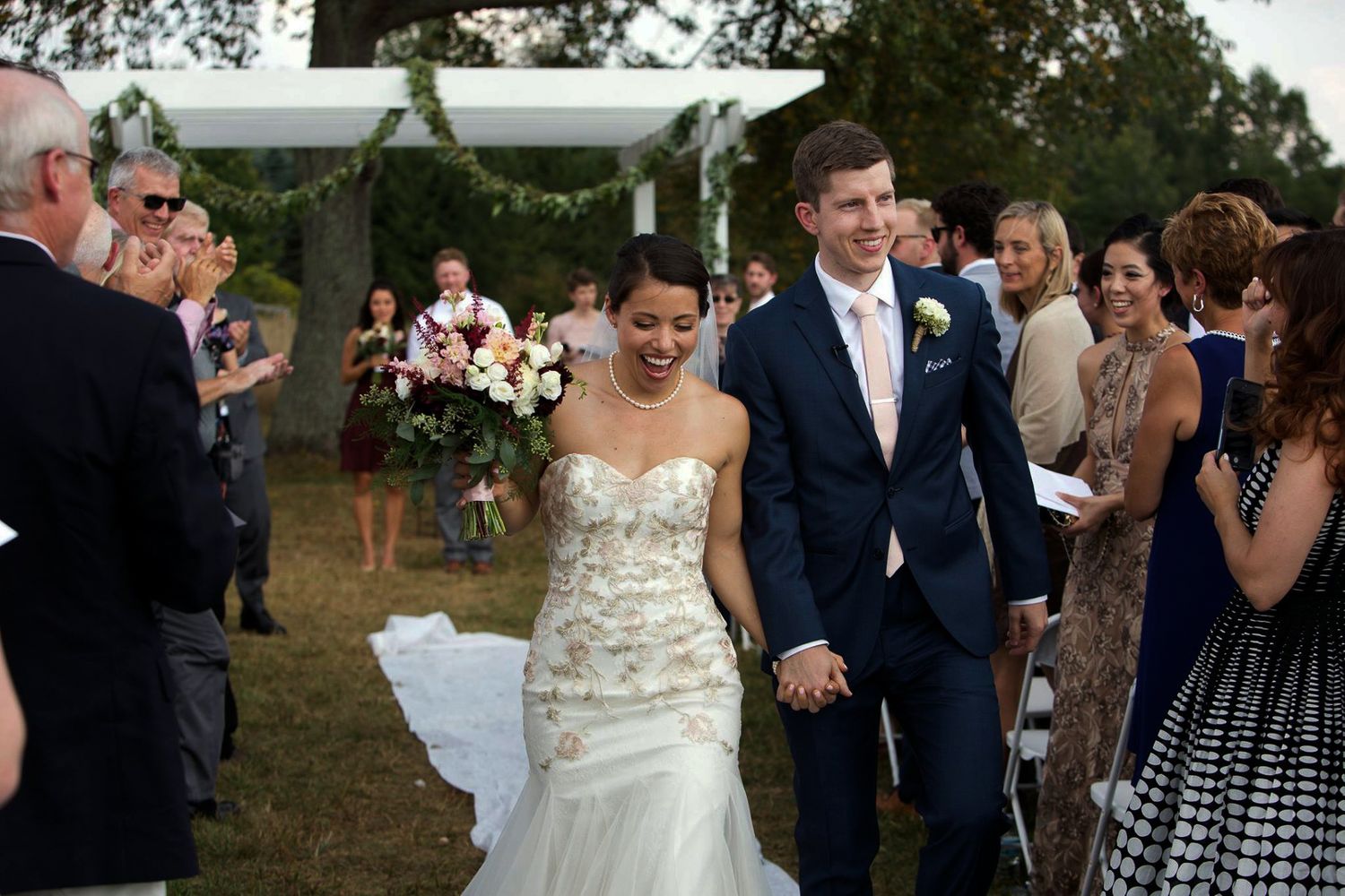 Wedding guests dance and celebrate during an outdoor evening reception with string lights overhead.