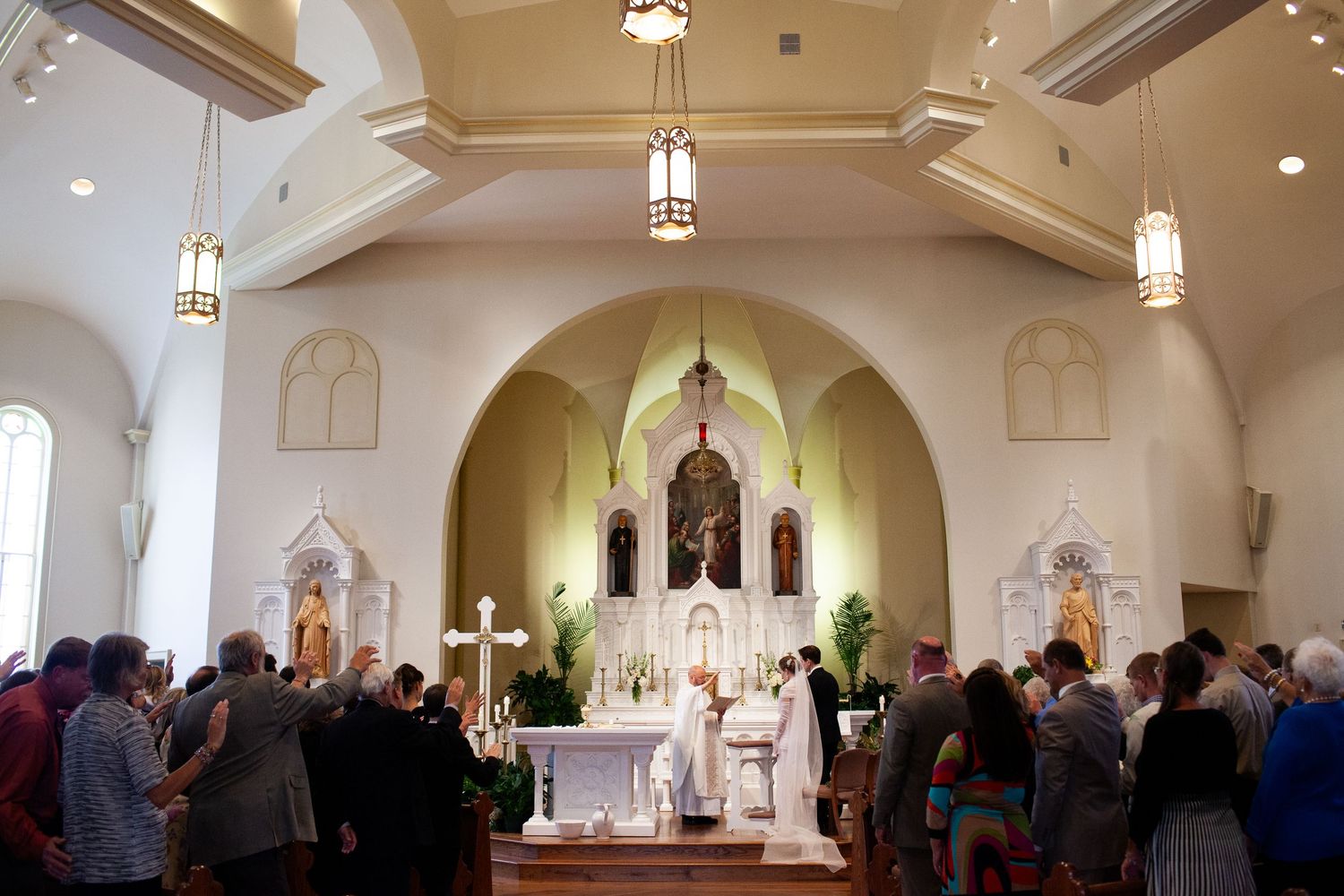 Traditional Catholic church wedding ceremony with vaulted ceilings and gathered congregation.