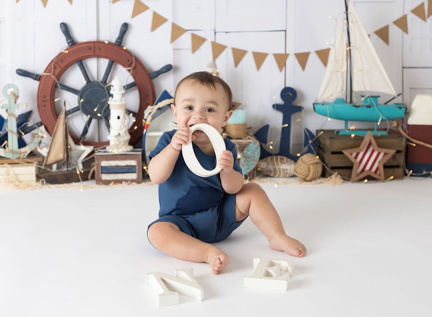 Rustic cake smash setup with bunting flags and nautical decorations against white backdrop.