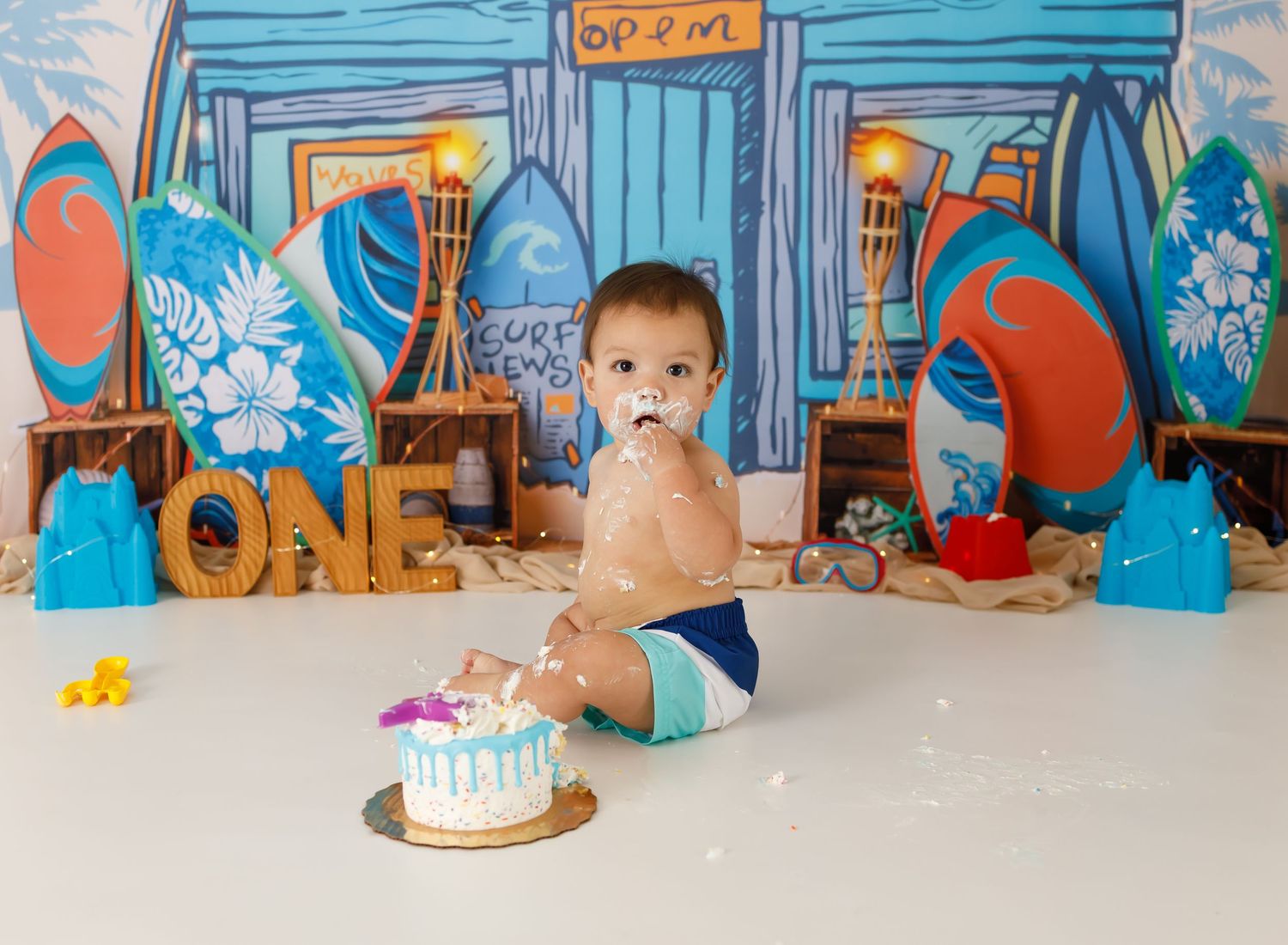 Under the sea themed cake smash setup with blue painted backdrop and ocean decorations.