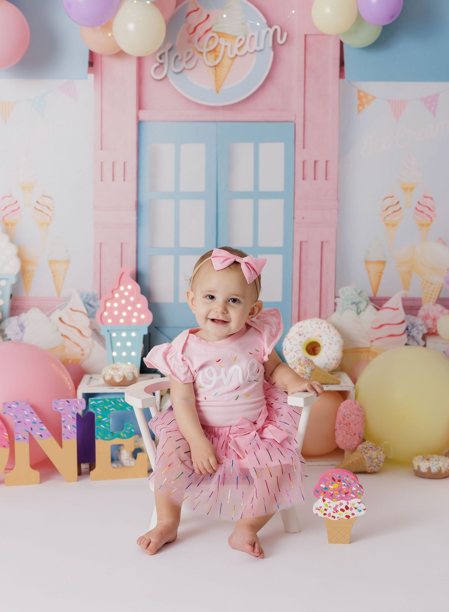 Ice cream parlor themed cake smash setup with pink walls and sweet treat decorations.