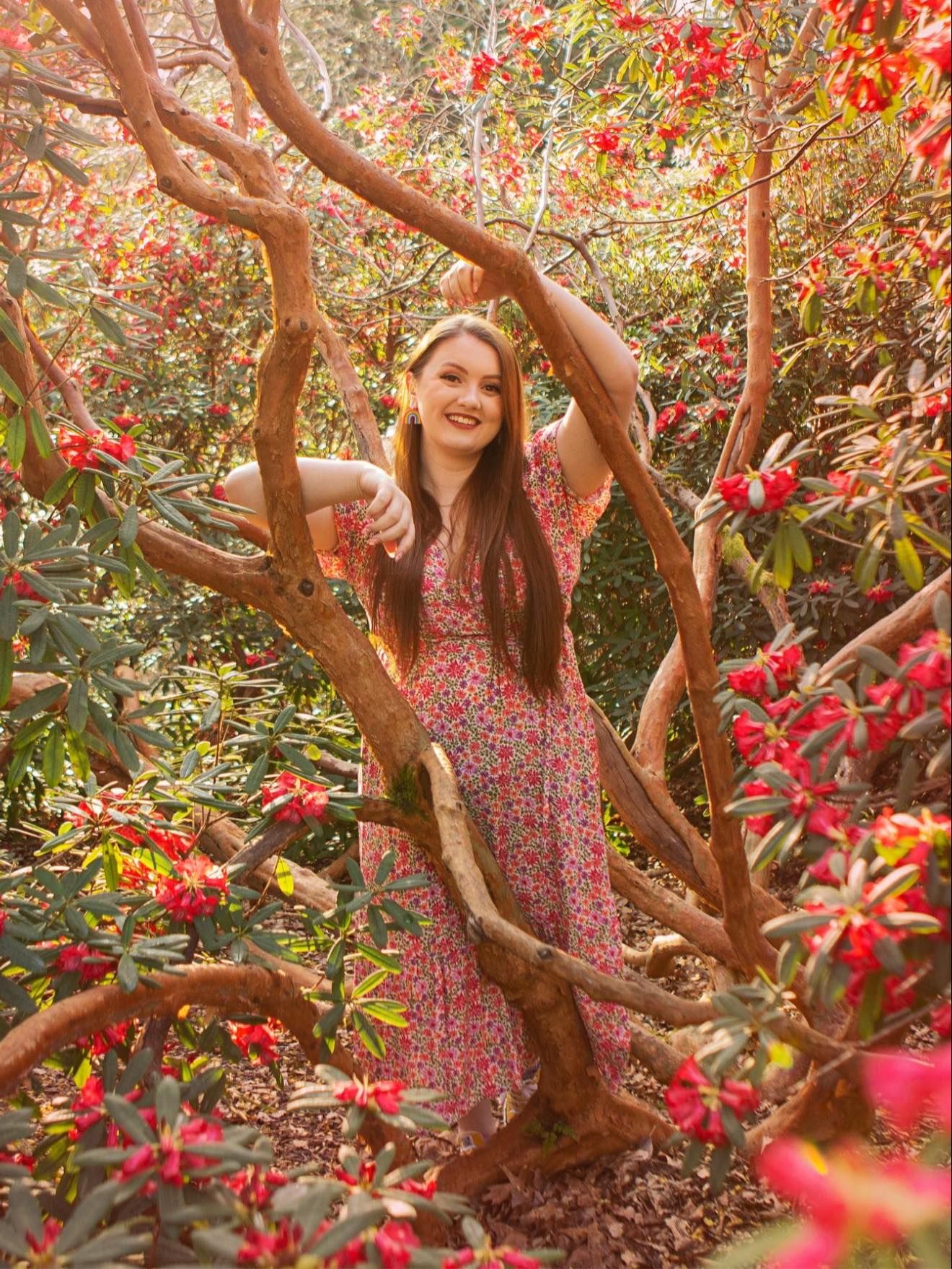Spring portrait session among blooming red flowers and twisted tree branches.
