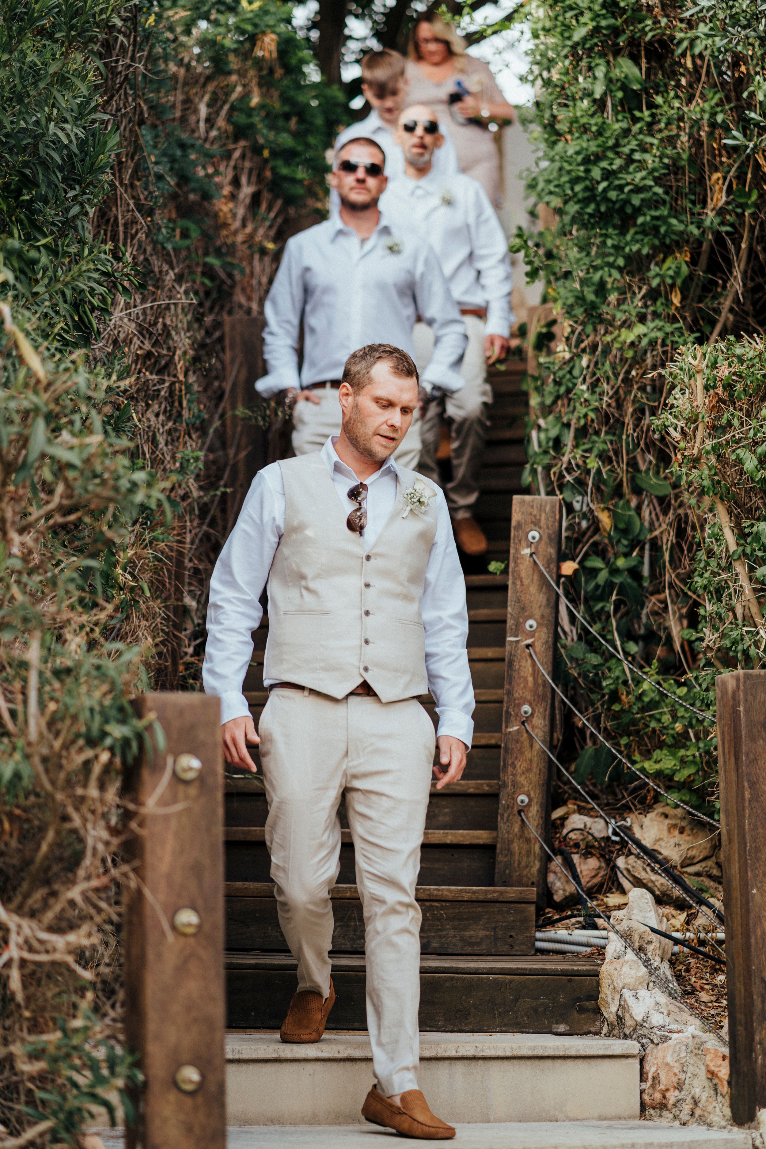 A series of photos showing a person in a light colored suit walking down wooden steps in an outdoor garden setting.