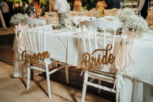 Elegant wedding reception tables decorated with white linens, floral centerpieces and gold accents in a rustic venue.