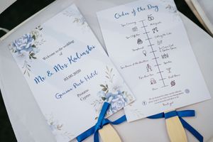 Wedding stationery with blue floral designs and seating charts laid out on a white surface.