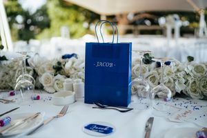 Elegant wedding table settings with white roses, crystal glasses and navy blue accents.