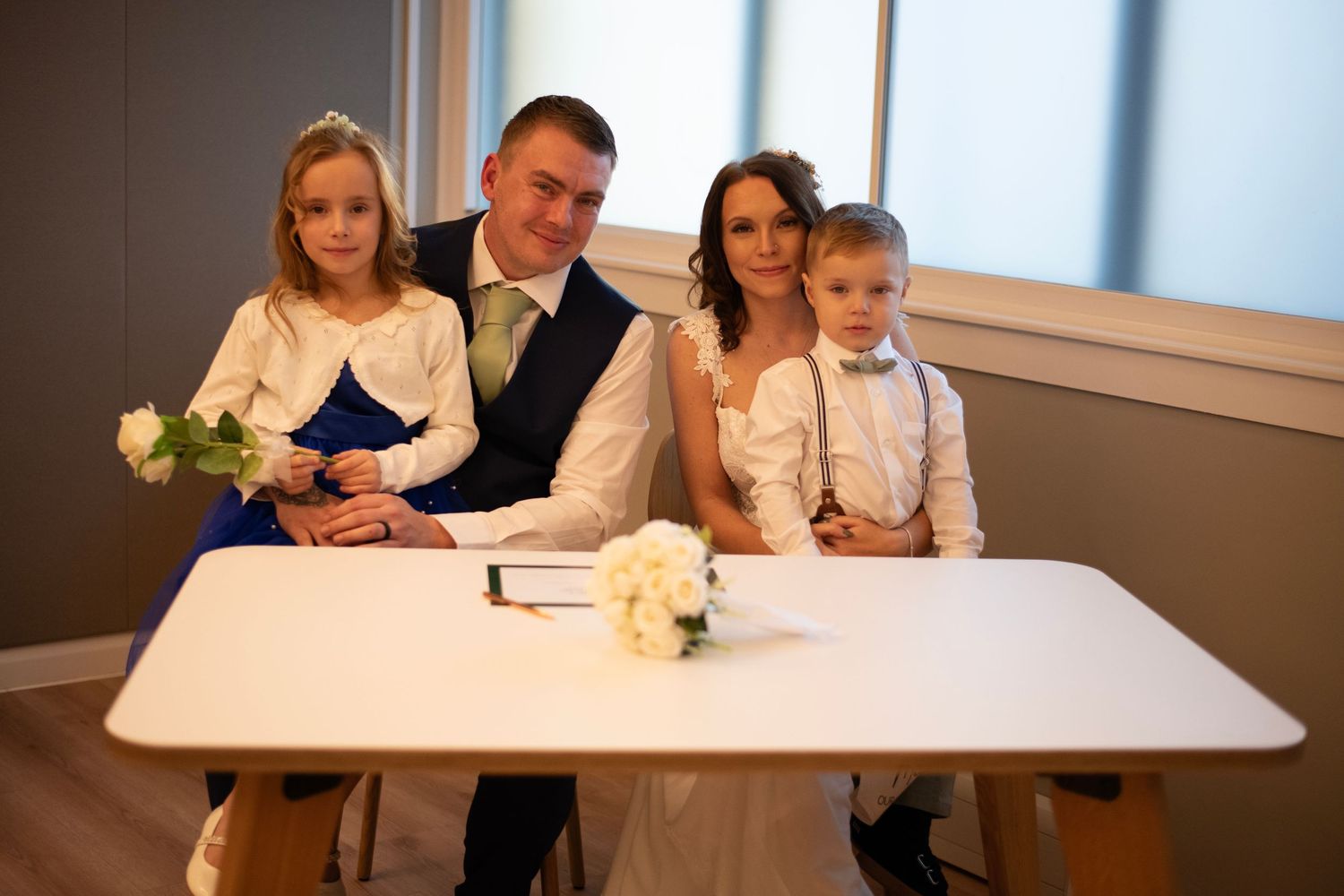 A group sits at a white table in a bright room with floral decorations and a modern interior design aesthetic.