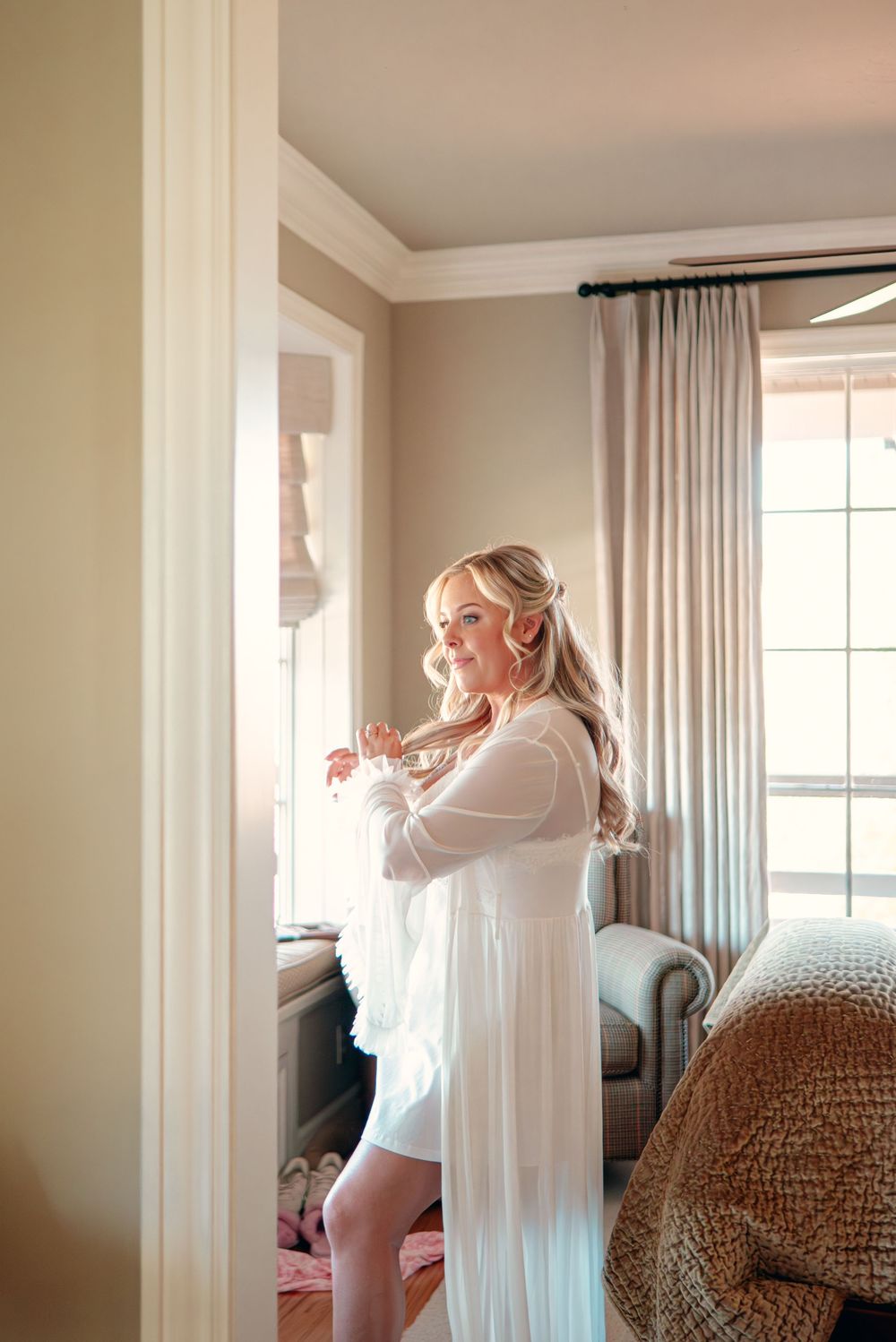 Light-filled bedroom interior with white curtains and neutral decor.