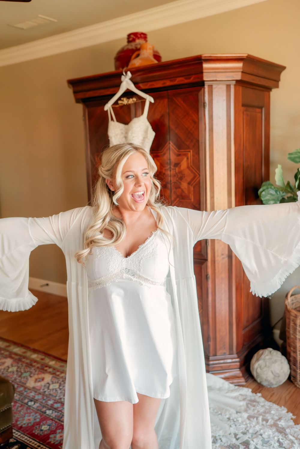 White silk robe being playfully modeled in a bedroom with wooden furniture.
