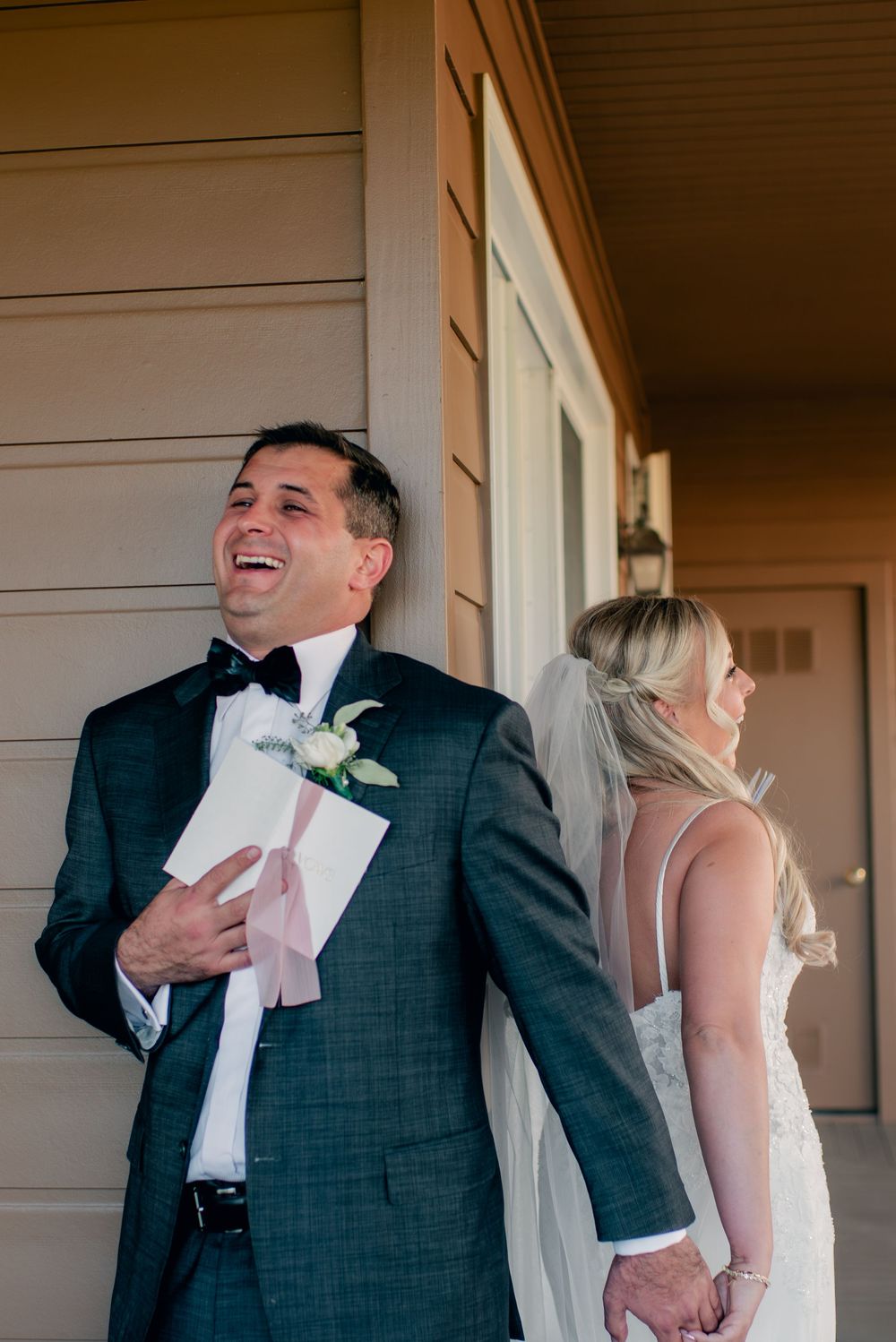 A wedding first look moment outside a building with joyful expressions.