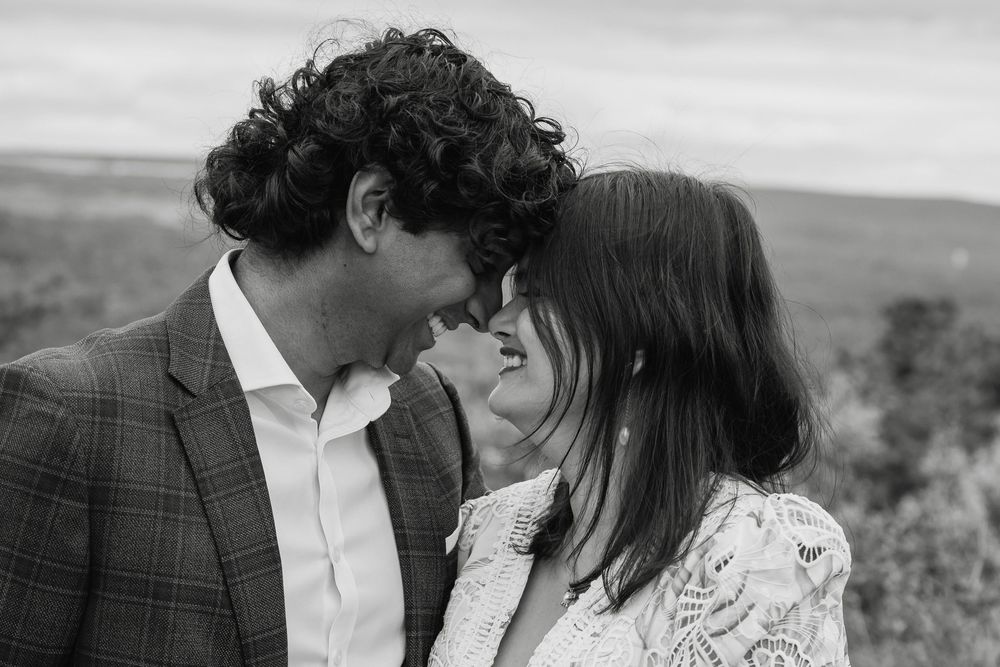 Black and white photo of couple touching foreheads intimately outdoors.