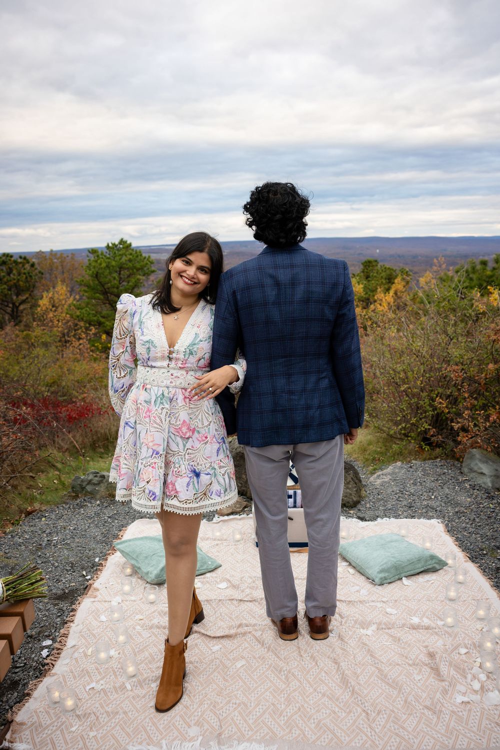 Couple standing on blanket overlooking stunning autumn valley landscape together.