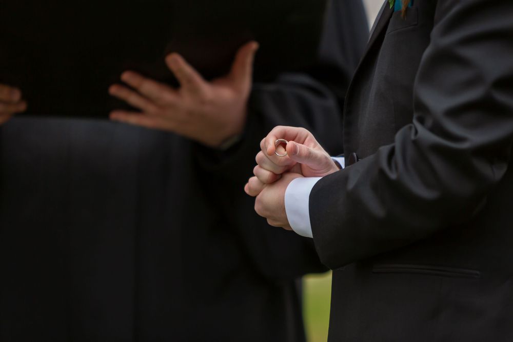 Closeup of groom holding wedding band during ceremony
