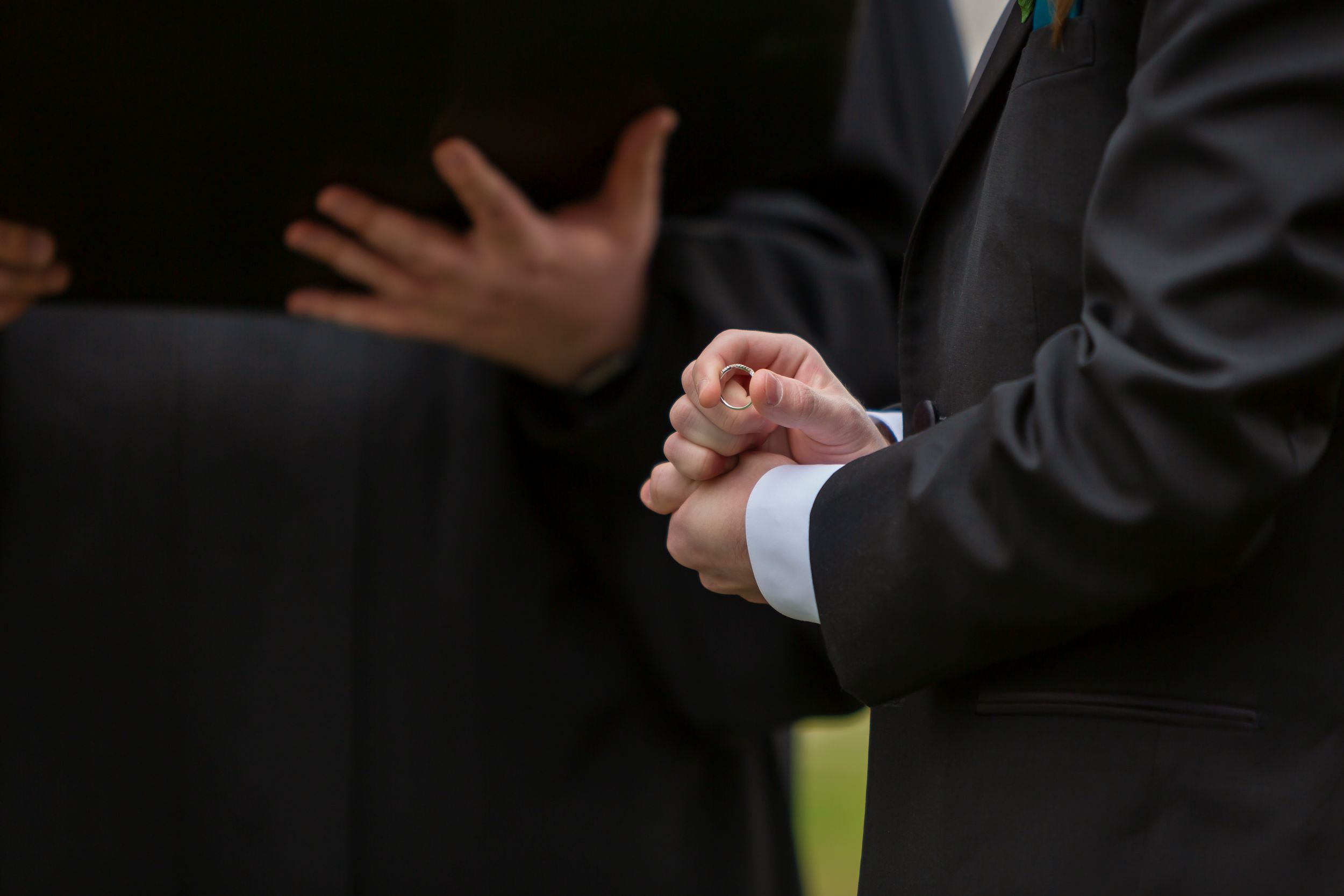 Closeup of groom holding wedding band during ceremony