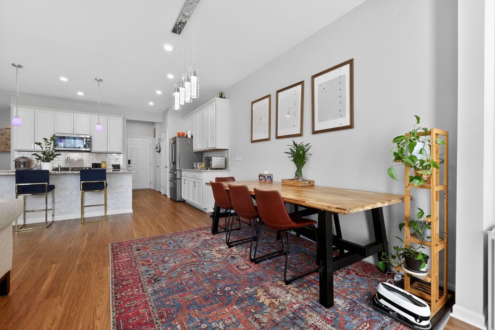 Open dining area with wood table, leather chairs, and modern kitchen with white cabinets beyond.