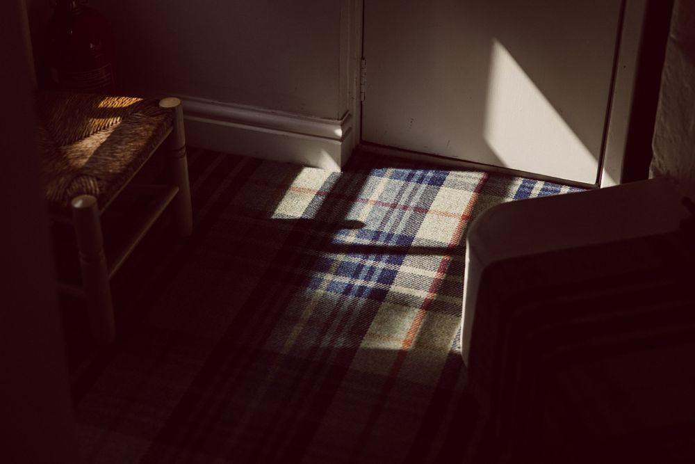 Sunlight streams through windows creating dramatic shadows and light patterns in a dimly lit interior space.