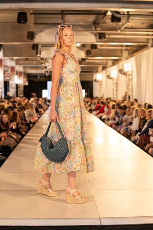 Floral print dresses and accessories displayed on runway at spring fashion show.
