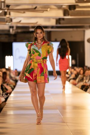 Colorful tropical print summer outfit displayed on illuminated fashion runway.