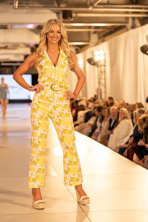 Yellow floral jumpsuit with belt detail showcased on illuminated runway.