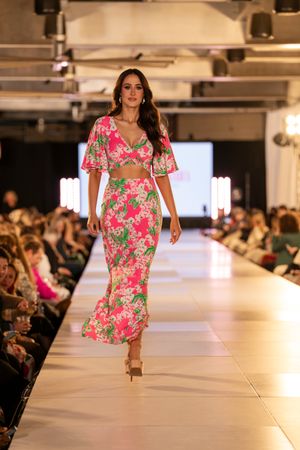 Bright pink floral dress with short sleeves presented during fashion show.