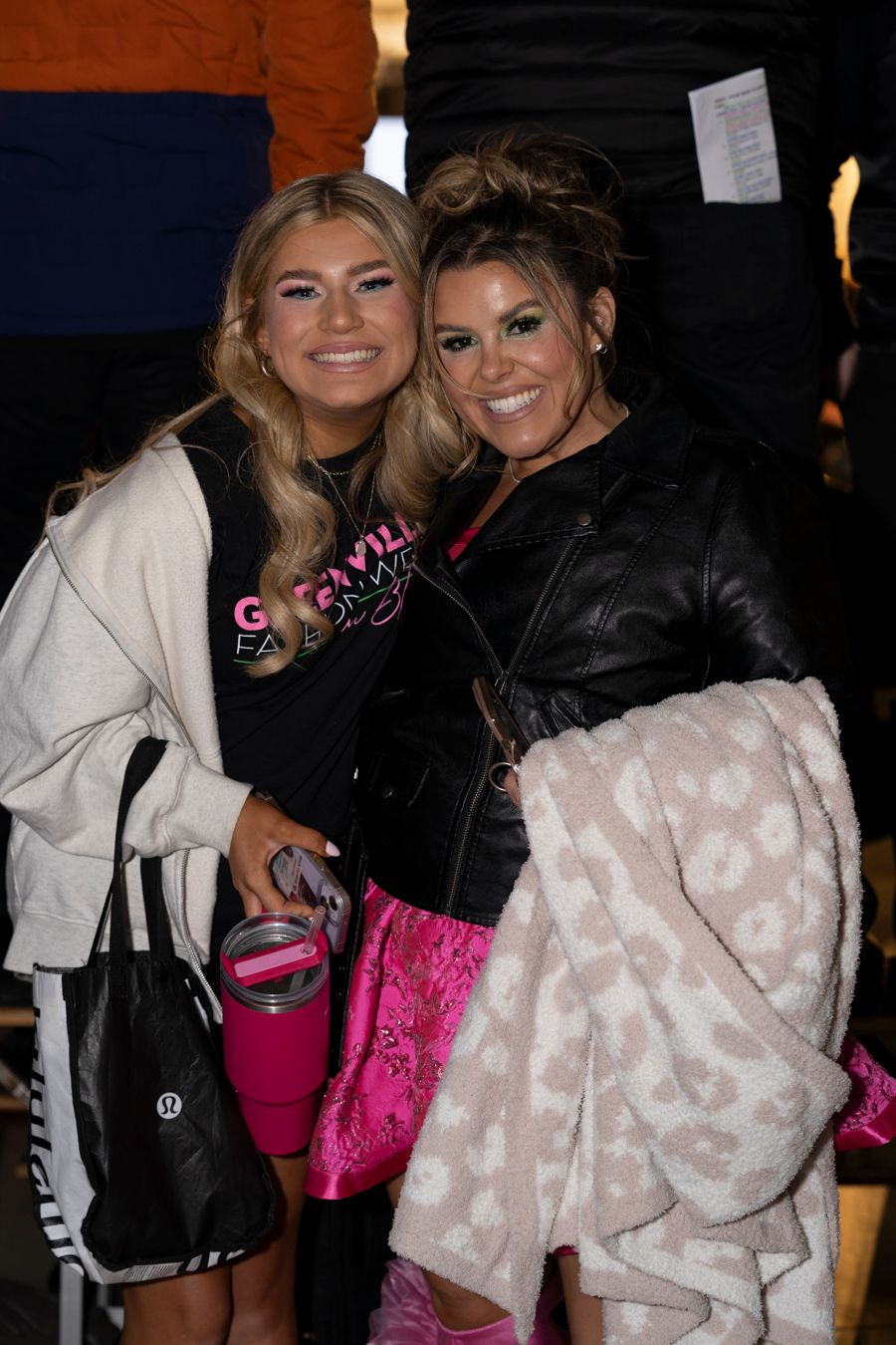 Two people posing together at a social event wearing contrasting black and white outfits with pink accessories.